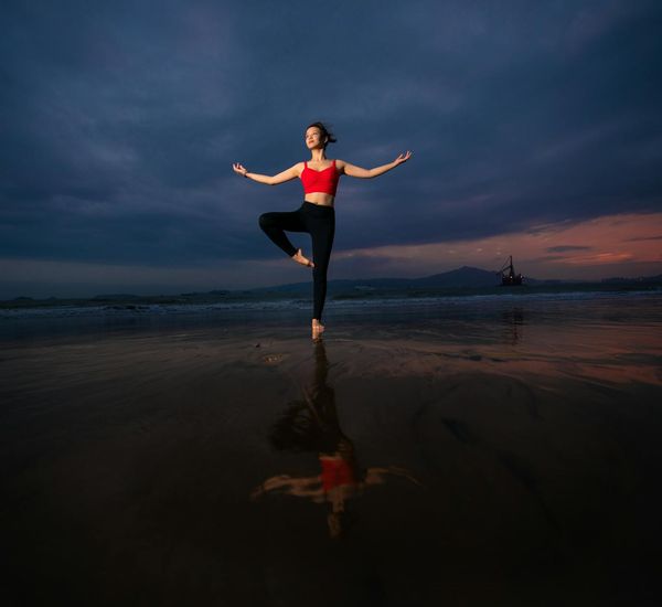 Silhouette of a person doing yoga against a vibrant sunset.